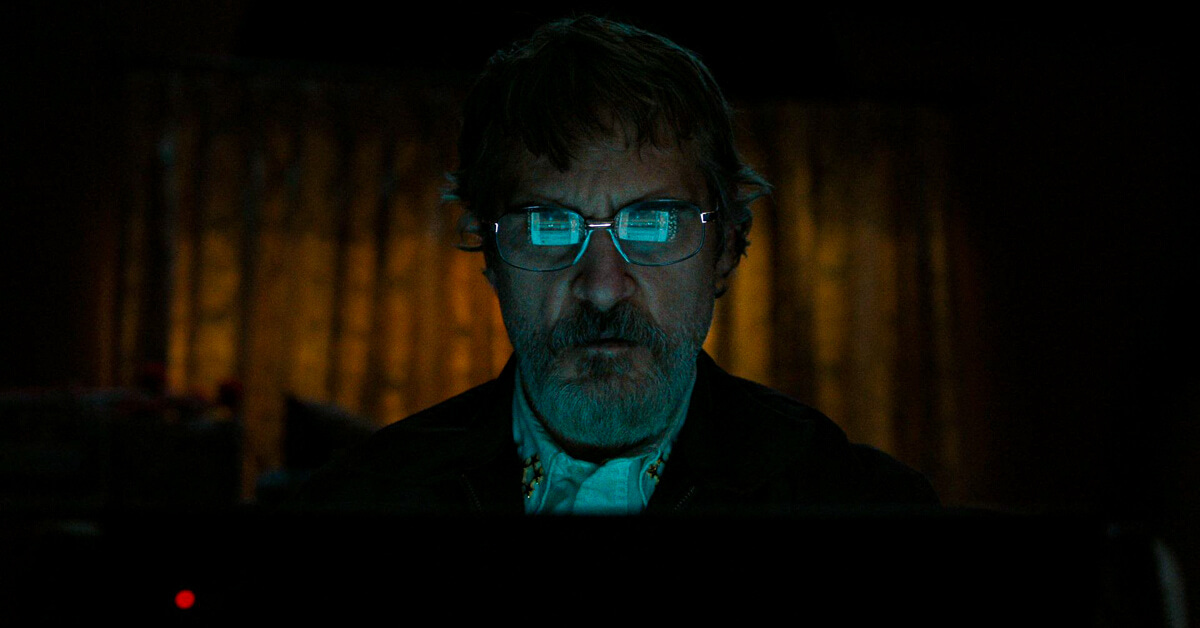 Joaquin Phoenix lit by his computer screen in a dark room, the display reflected across both lenses of his glasses. Joaquin Phoenix lit by his computer screen in a dark room, the display reflected across both lenses of his glasses.