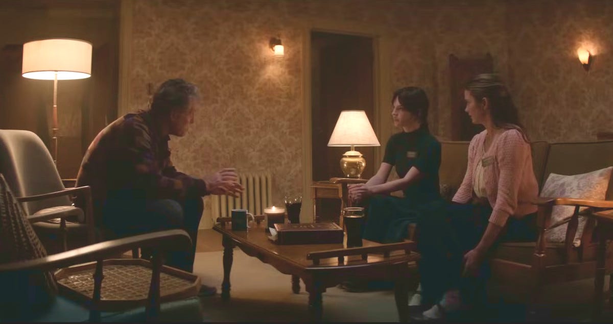 Older man sitting on a chair and facing and talking with two young women who are also seated Older man sitting on a chair and facing and talking with two young women who are also seated