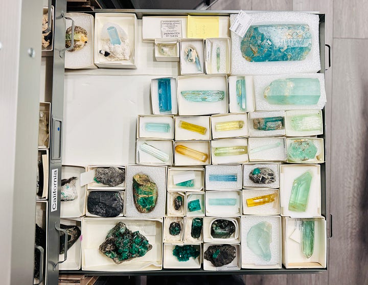 Open specimen drawers in the mineral research collection at the Natural History Museum of Los Angeles County, showing rows of labeled minerals including beryl, corundum, spodumene, opals, quartz, and feldspar, each specimen boxed and catalogued.