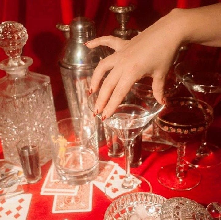 This may contain: a table topped with lots of glassware and silver ware on top of a red cloth