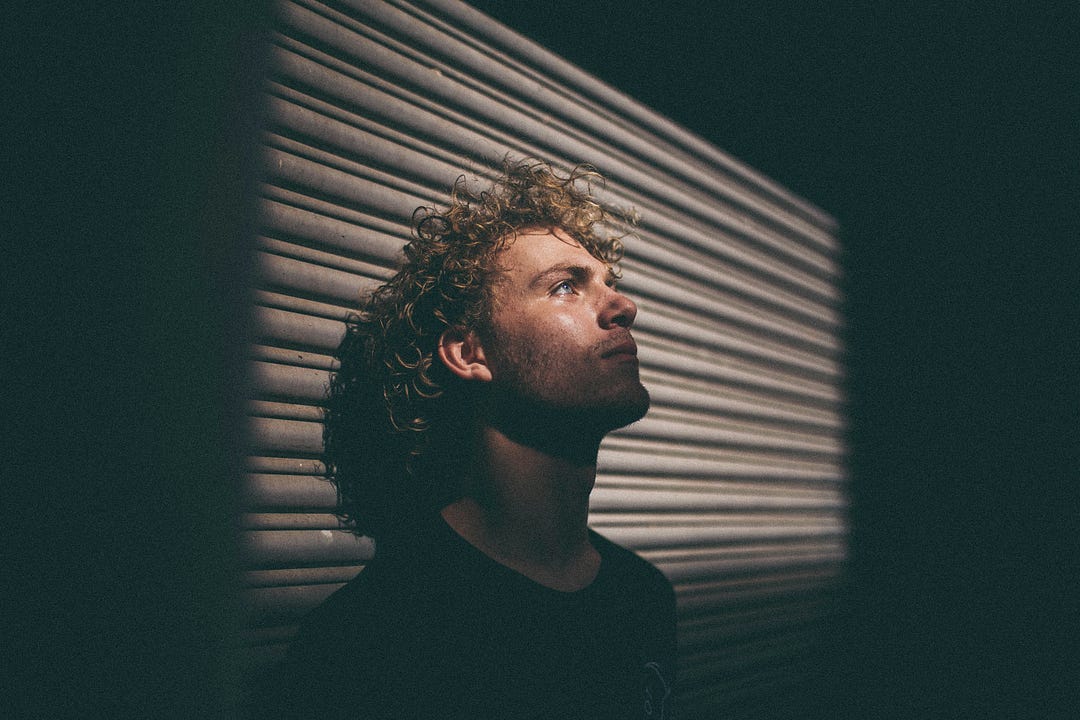 A man pensively sitting in the dark, thinking about his past and regretting some of his decisions. A man pensively sitting in the dark, thinking about his past and regretting some of his decisions.