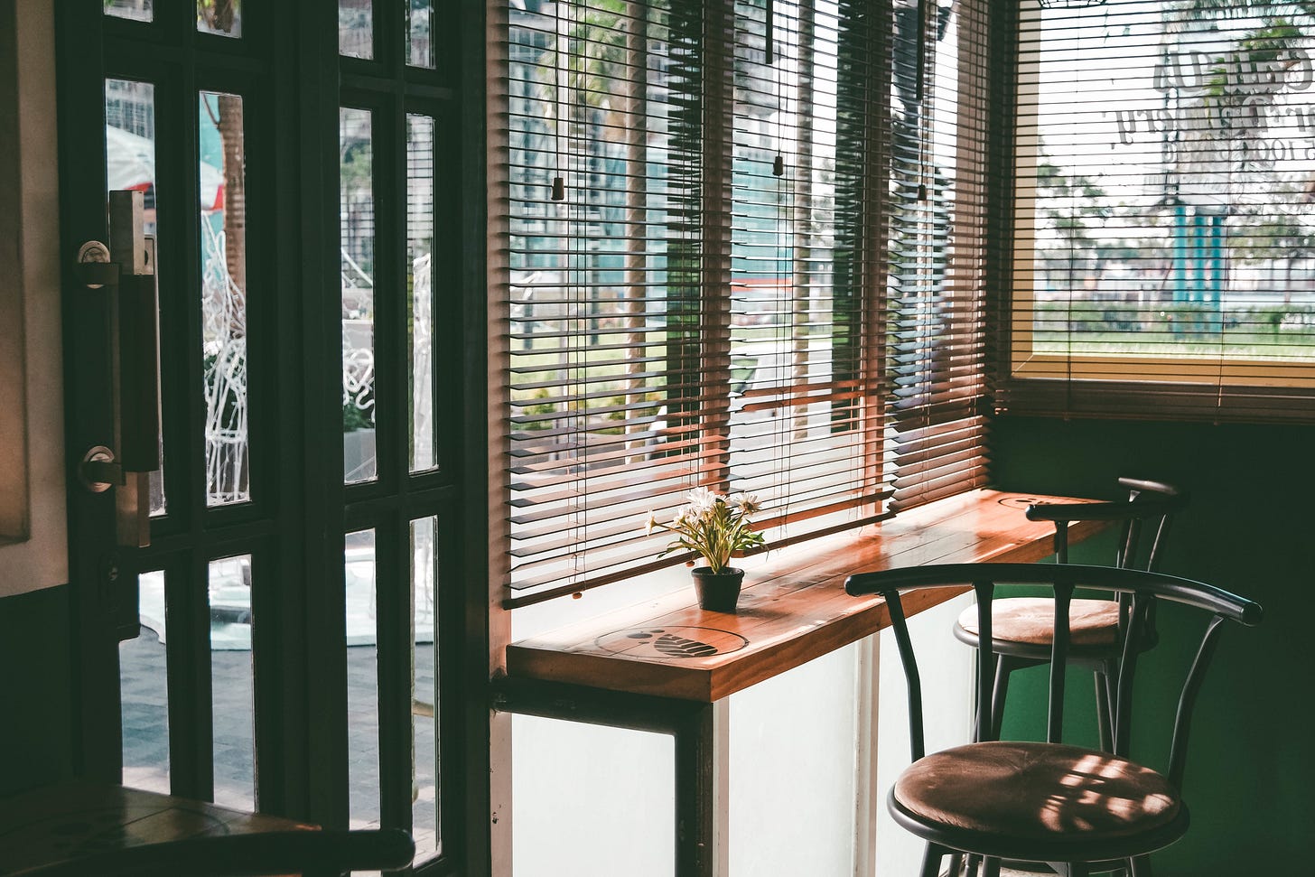 Photo of two empty chairs in a cafe by a window and shadowy blinds Photo of two empty chairs in a cafe by a window and shadowy blinds