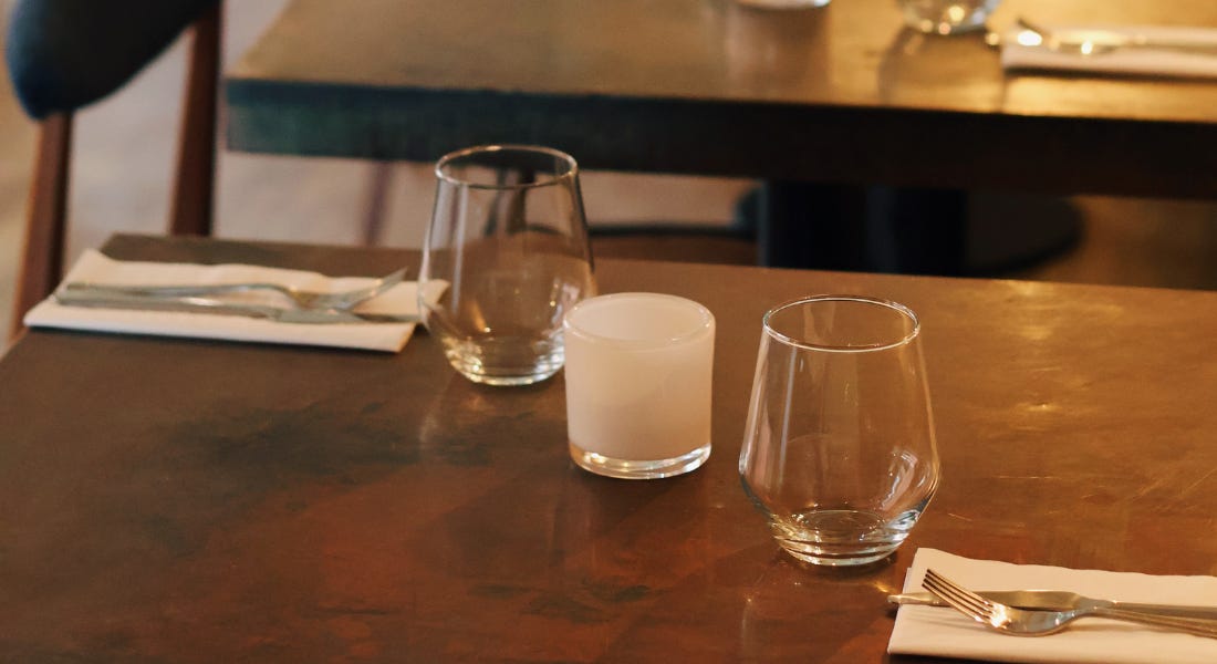 A close-up of a copper table with knives and forks and glasses on top of it