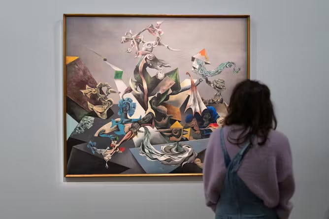 Person shown from behind standing in front of large colorful painting on gallery wall 