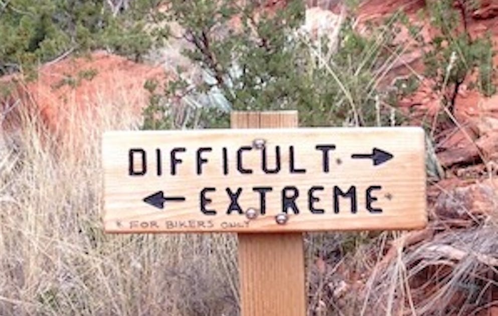 Trail sign. Arrow to the right labeled "Difficult" and arrow to the left labelled "Extreme"
