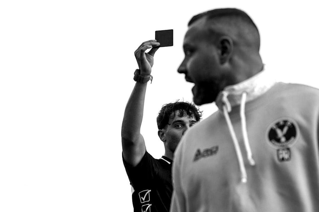 A man in a green hoodie holding up a red card