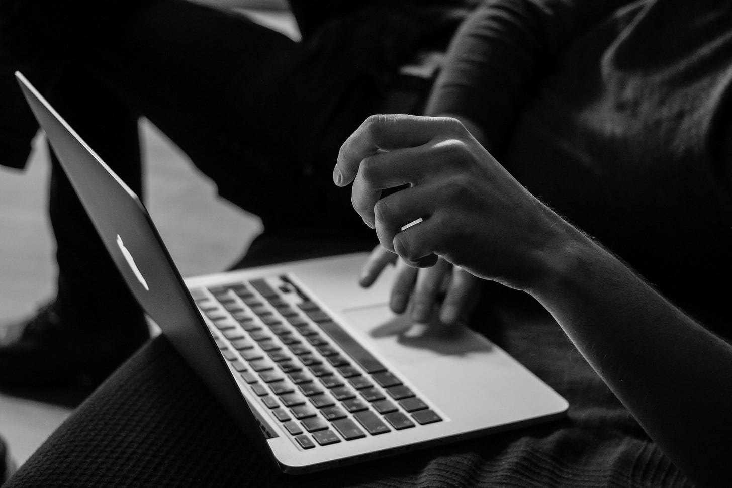 grayscale photo of a person using a macbook