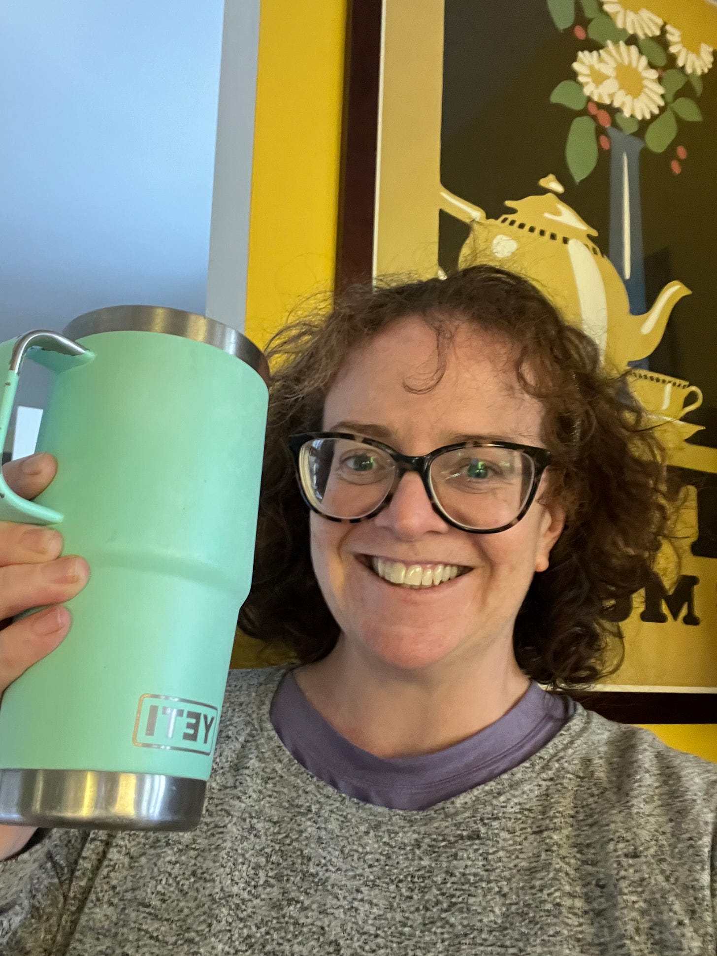 Woman holding a travel thermos grinning