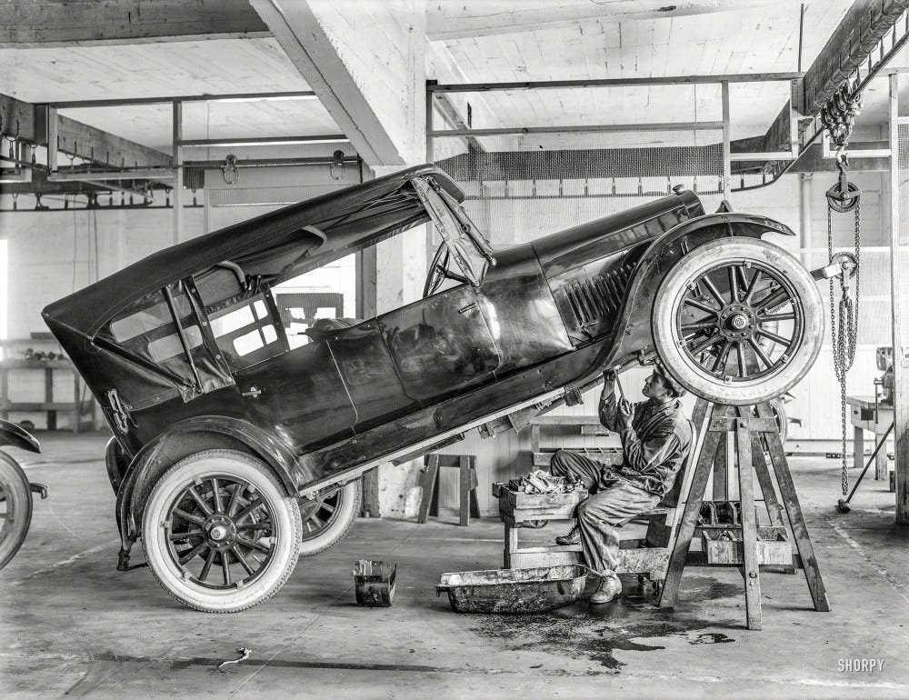 Circa 1919. "Studebaker motor car in repair shop with garage mechanic." Don't try this at home. Or at work. 6.5 x 8.5 inch glass negative from the Wyland Stanley collection of San Francisco historical memorabilia. 