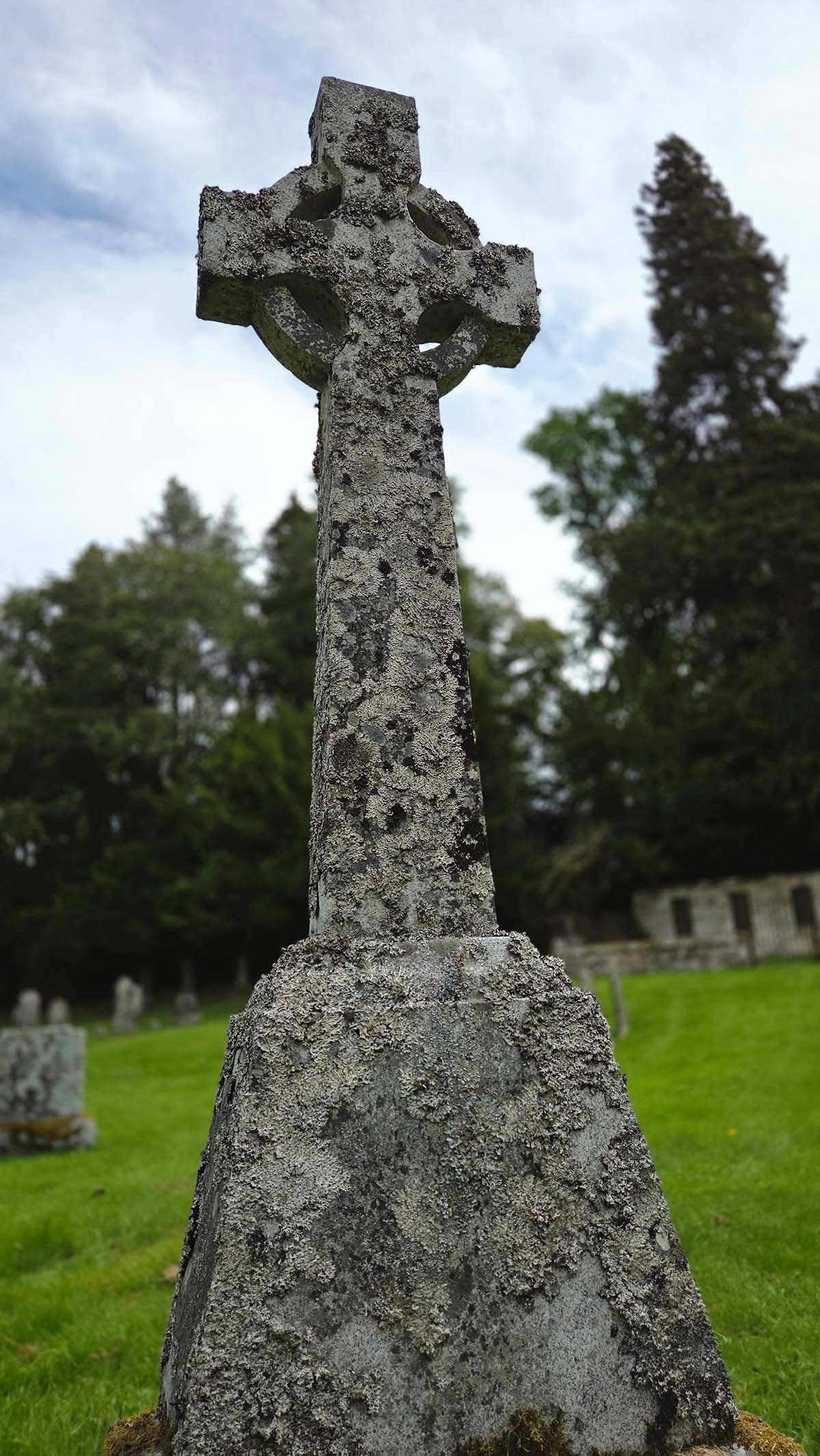 A lichen covered Celtic cross in a cemetery. 
