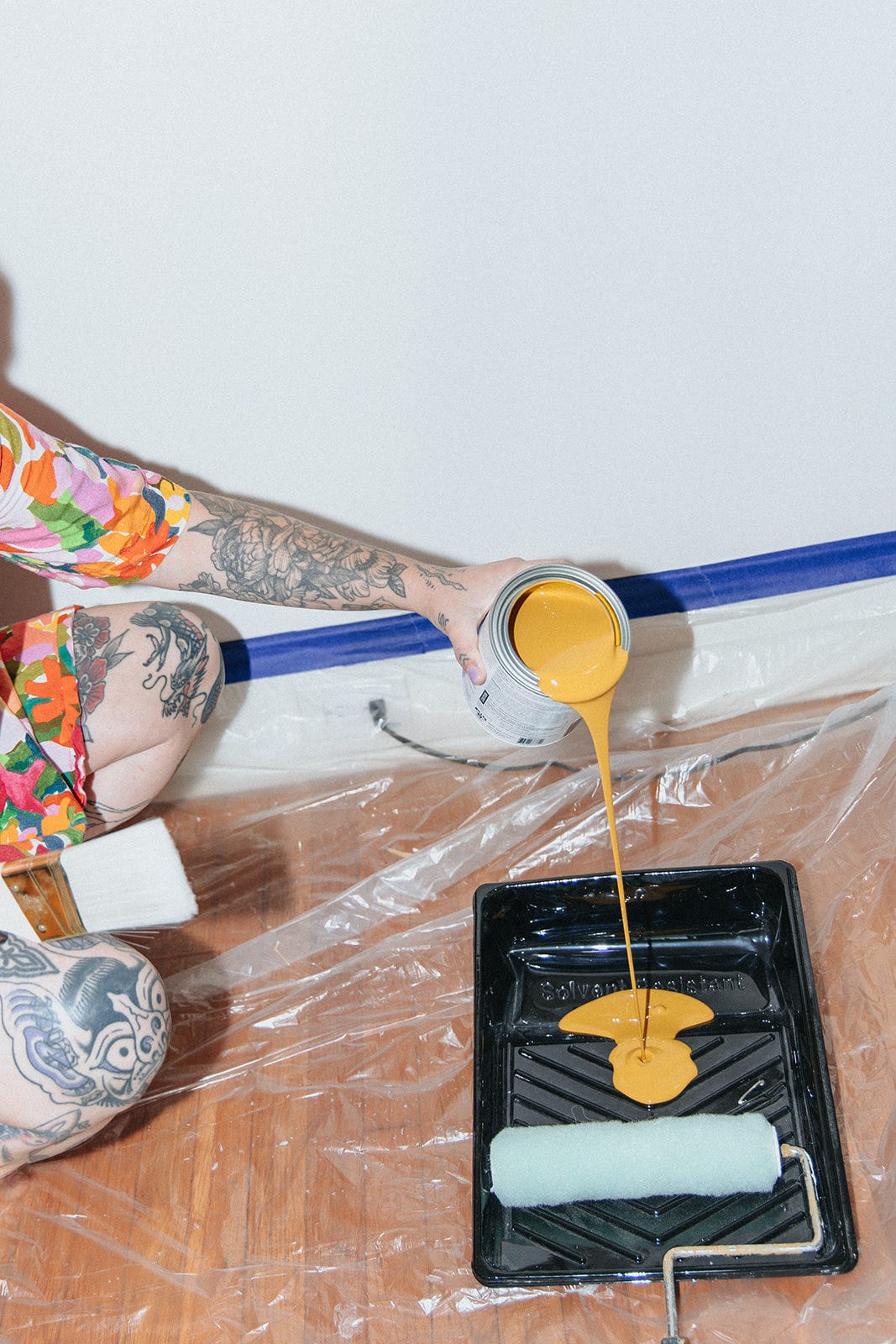Woman pours a mustard yellow paint out of a can into a paint tray