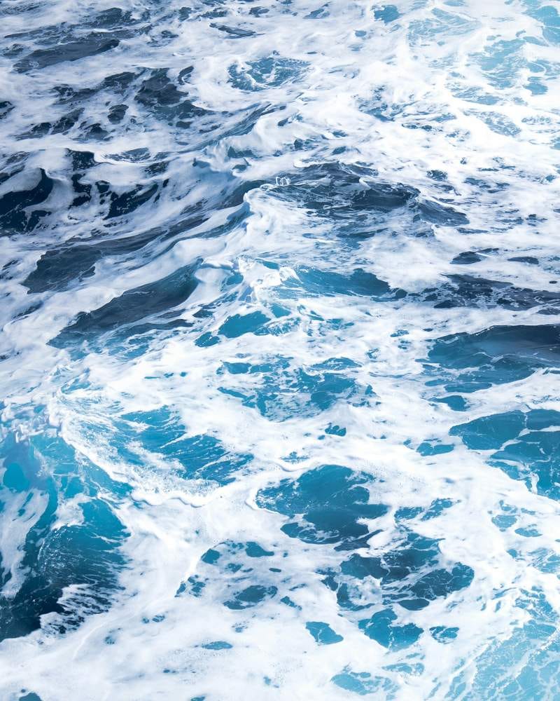 Photo of choppy blue-green sea water marbled with foam.
