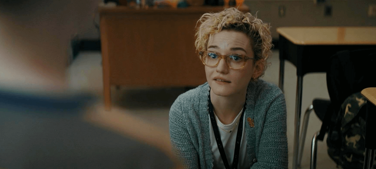 Professora de óculos e cabelo curto e cacheado conversa com alguém em sala de aula, com expressão atenta e empática. Professora de óculos e cabelo curto e cacheado conversa com alguém em sala de aula, com expressão atenta e empática.