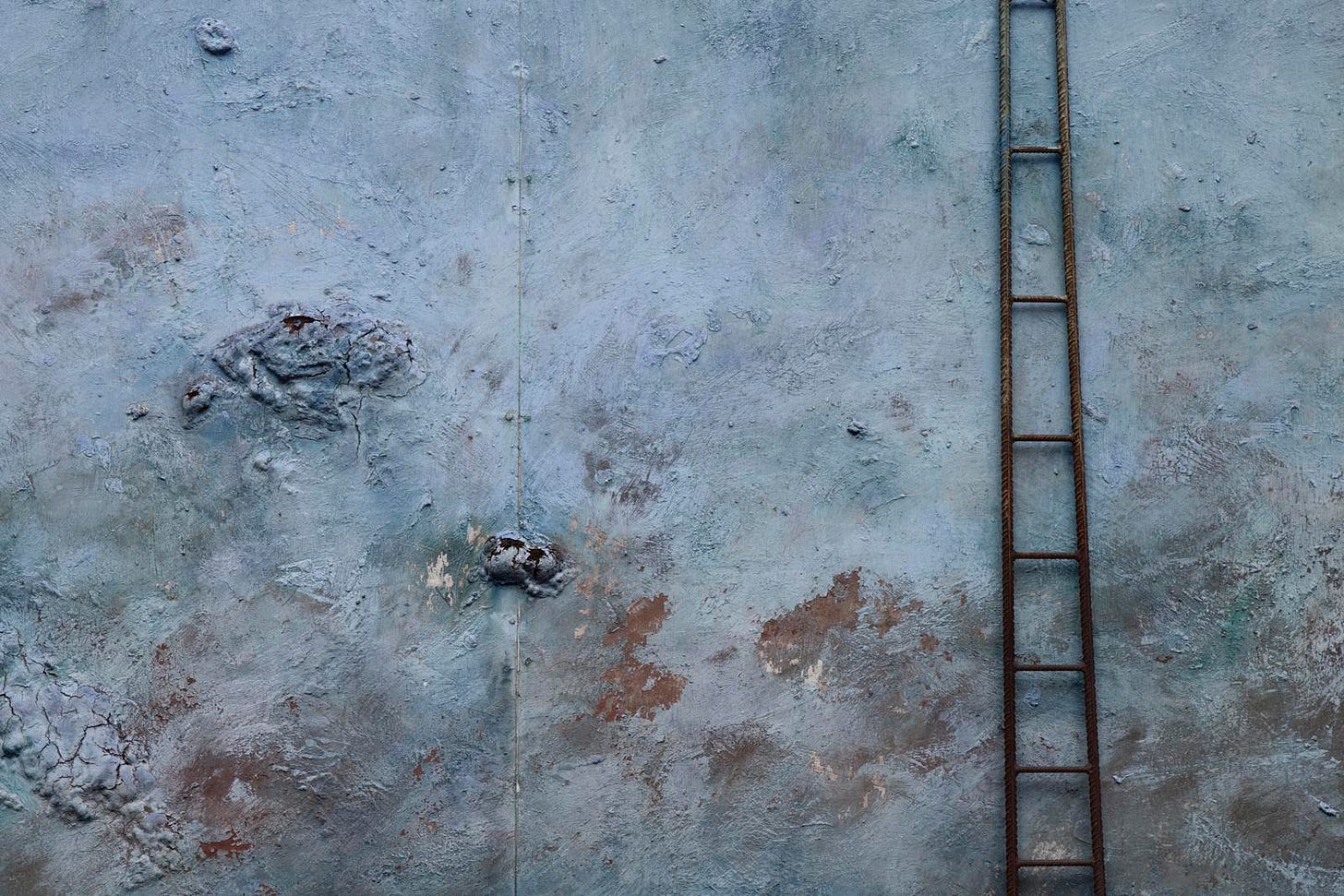 Old ladder leaving against an ancient blue wall