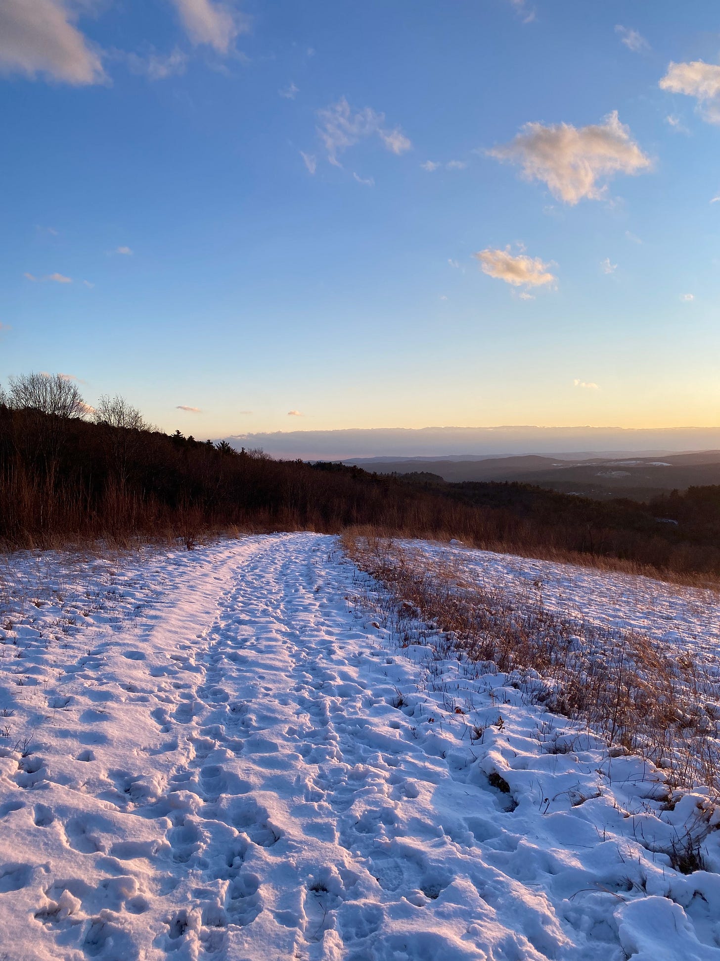 A sunny, snowy path along a ridgetop.