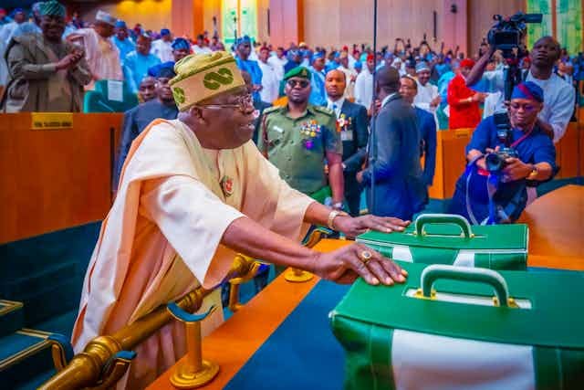 Man wearing full traditional attire placing two bags on a table