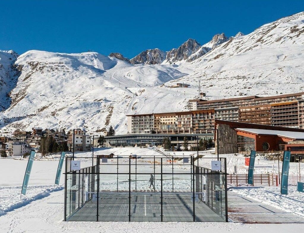padel court in ski resort with backdrop of snow covered mountains 
