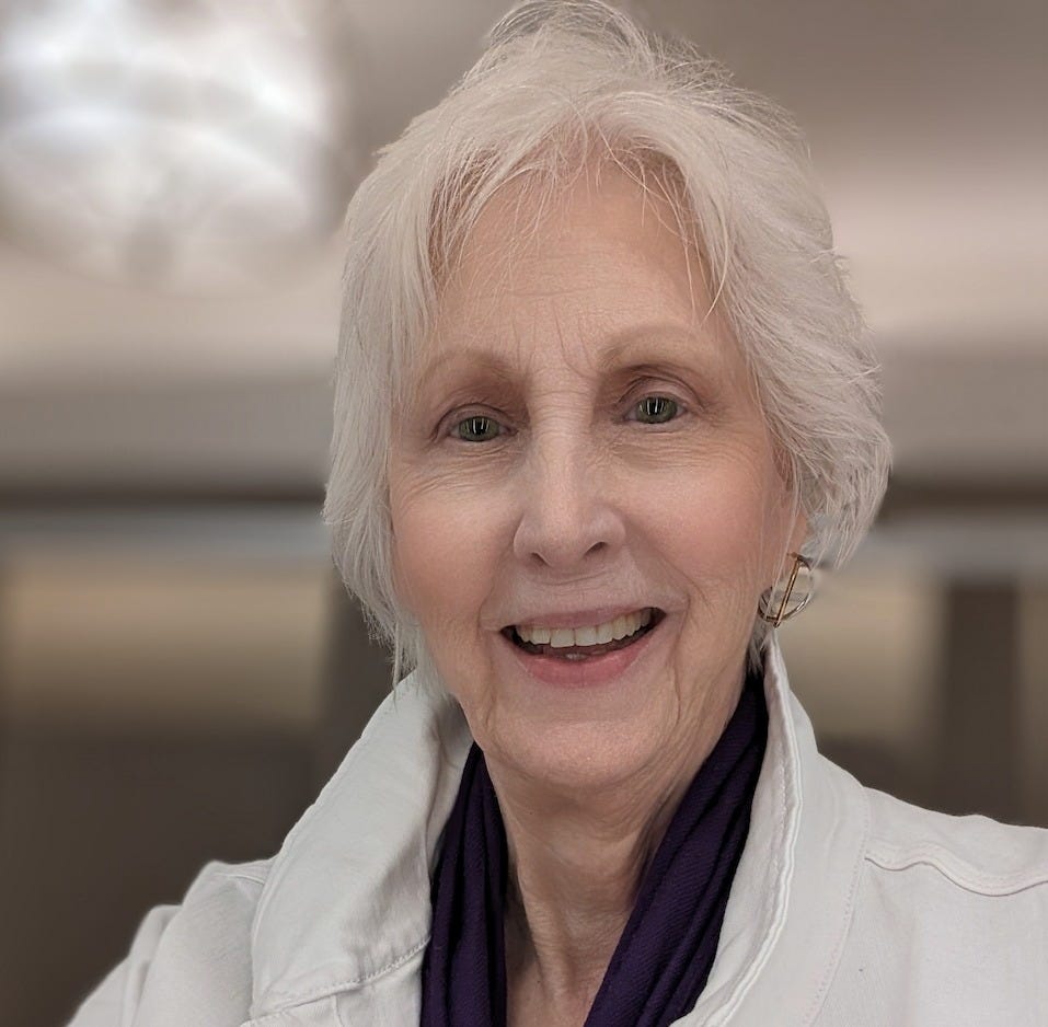 Selfie of Donna Blevins, the author, at 75, wearing a white jean jacket with a purple scarf and a gold earring showing on her left ear. She is proud of her well-earned wrinkles, her shaven chin, and her short, bright white hair. The background is blurred. Selfie of Donna Blevins, the author, at 75, wearing a white jean jacket with a purple scarf and a gold earring showing on her left ear. She is proud of her well-earned wrinkles, her shaven chin, and her short, bright white hair. The background is blurred.