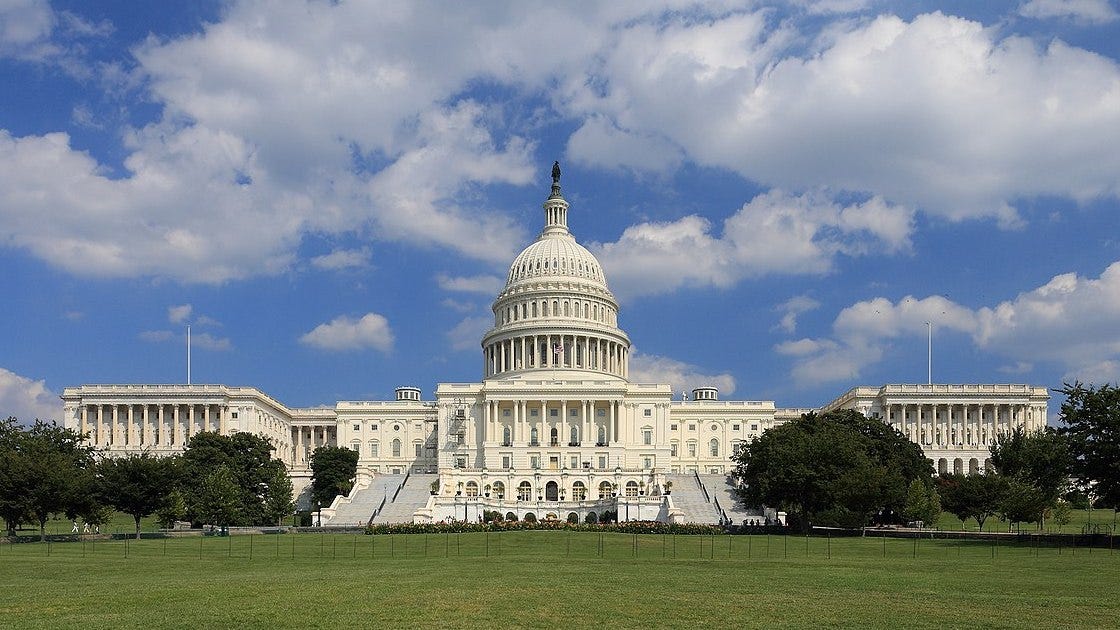 The west side of the US Capitol on a bright, partly cloudy day.