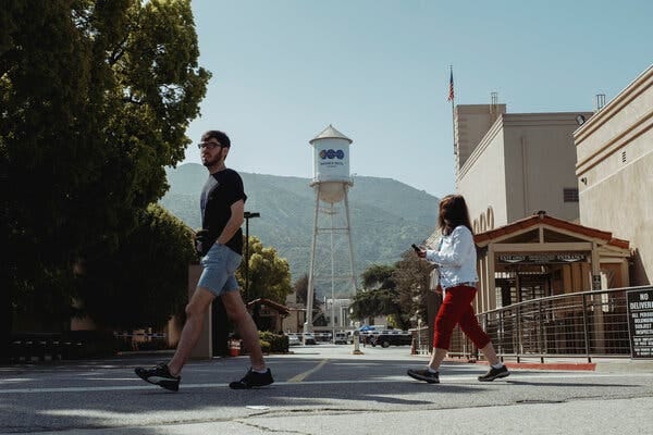 People walking around Warner Bros. Studio with a mountain visible in the background.