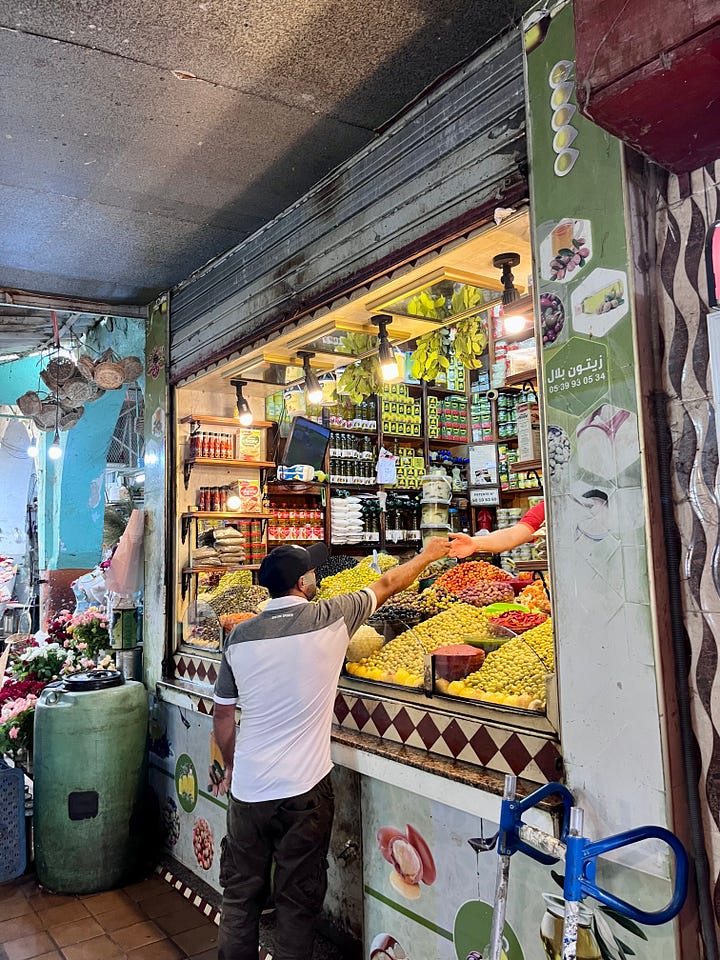 a picture of a market stall selling olives, a picture of a large pyramid of brown soap with the words inscribed 'savon' on