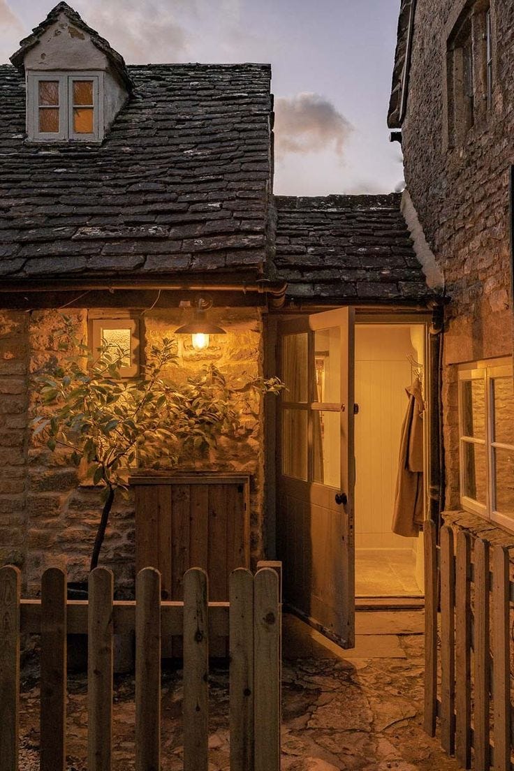 This may contain: an old stone building with a door and window lit up by the light at night