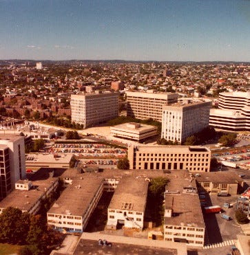 Aerial view of MIT Building 20, a three-storey plywood building in the foreground. Polaroid's headquarters visible behind.