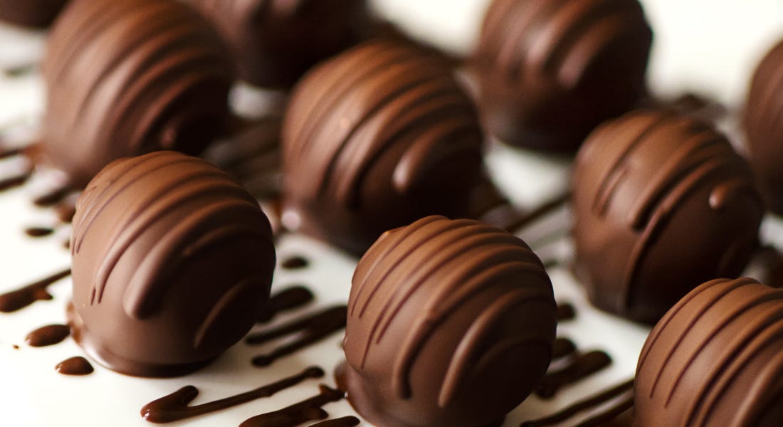 A plate with round dark chocolate truffles on top A plate with round dark chocolate truffles on top