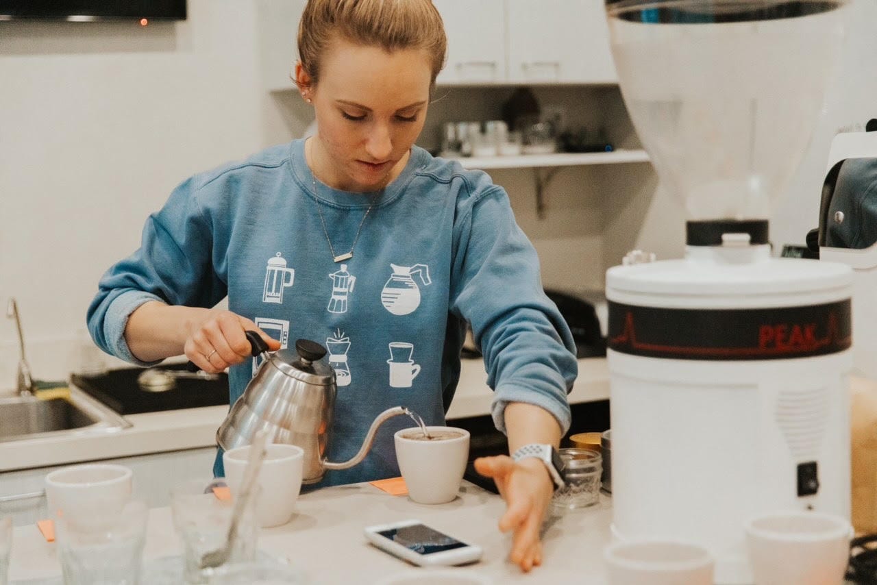 Breanna Briggs, head coffee roaster at Leap coffee pouring water from a hot kettle into a coffee cupping mug in the lab at Leap coffee. Breanna Briggs, head coffee roaster at Leap coffee pouring water from a hot kettle into a coffee cupping mug in the lab at Leap coffee.