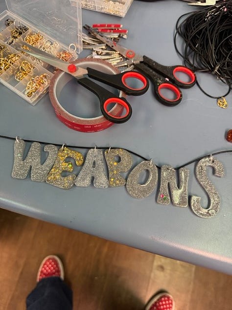 Images show Weapon S and J necklaces plus a gift wrapped box