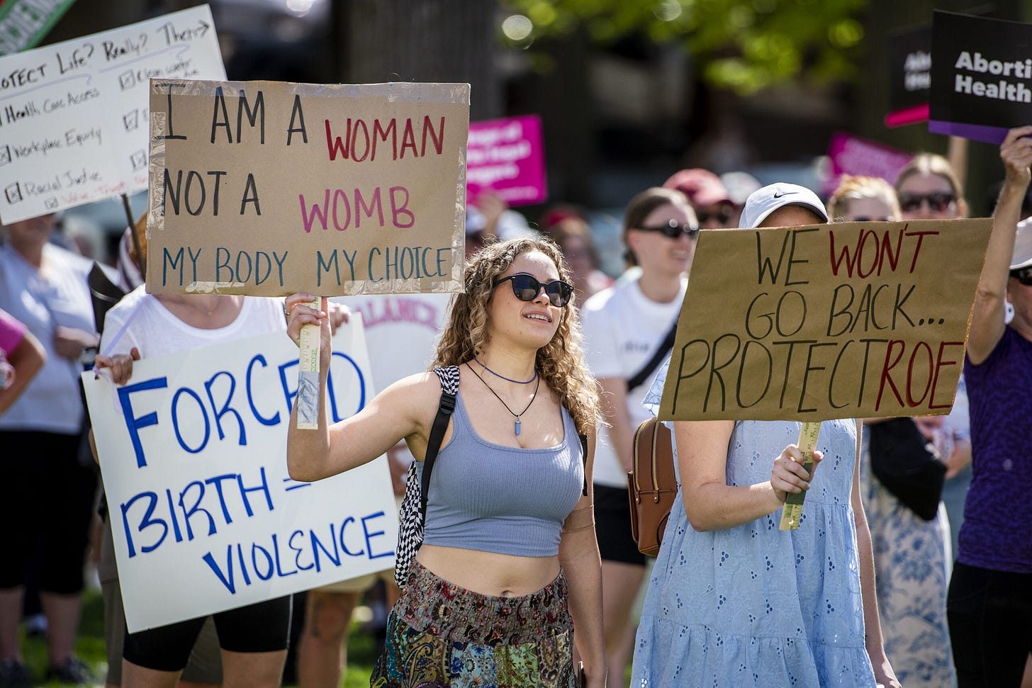 A photo of a pro-choice rally, showing a group of people holding up signs in support of abortion access. A photo of a pro-choice rally, showing a group of people holding up signs in support of abortion access.