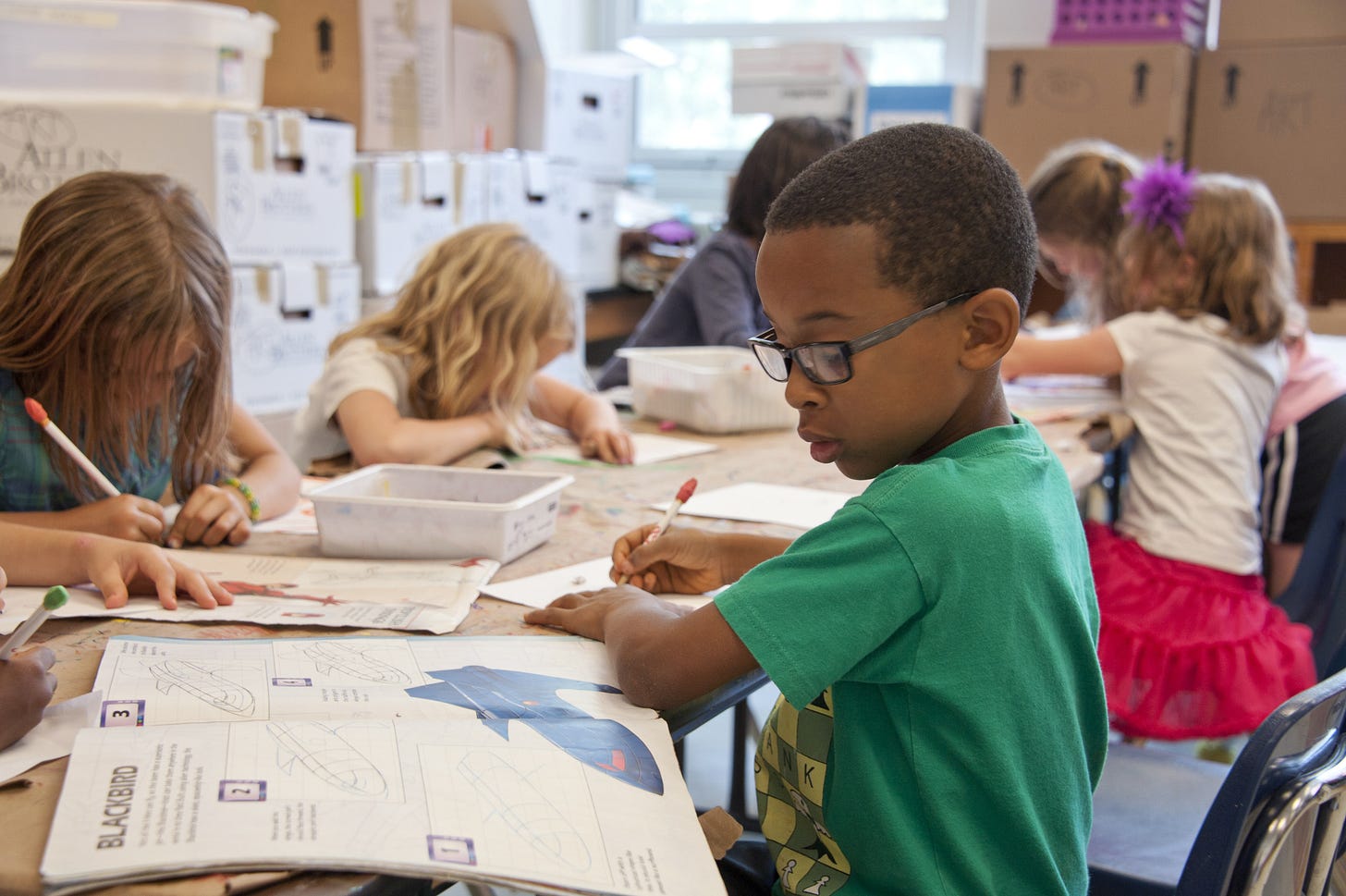  Boy in green t-shirt completing classroom activity