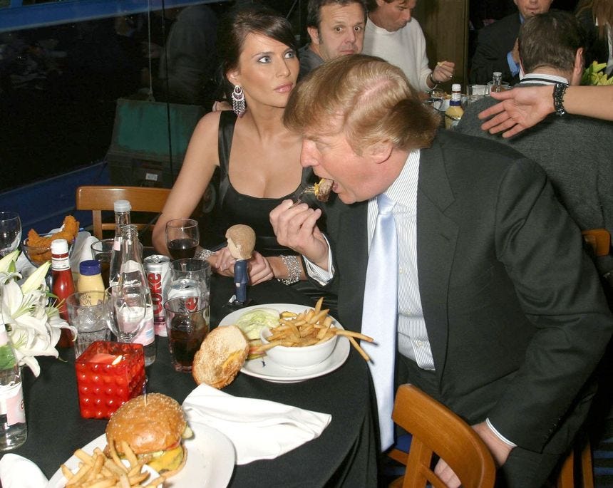 L'image peut contenir une personne, un hamburger, de la nourriture, Melania Trump, un repas au restaurant, un costume, un manteau, des vêtements. L'image peut contenir une personne, un hamburger, de la nourriture, Melania Trump, un repas au restaurant, un costume, un manteau, des vêtements.