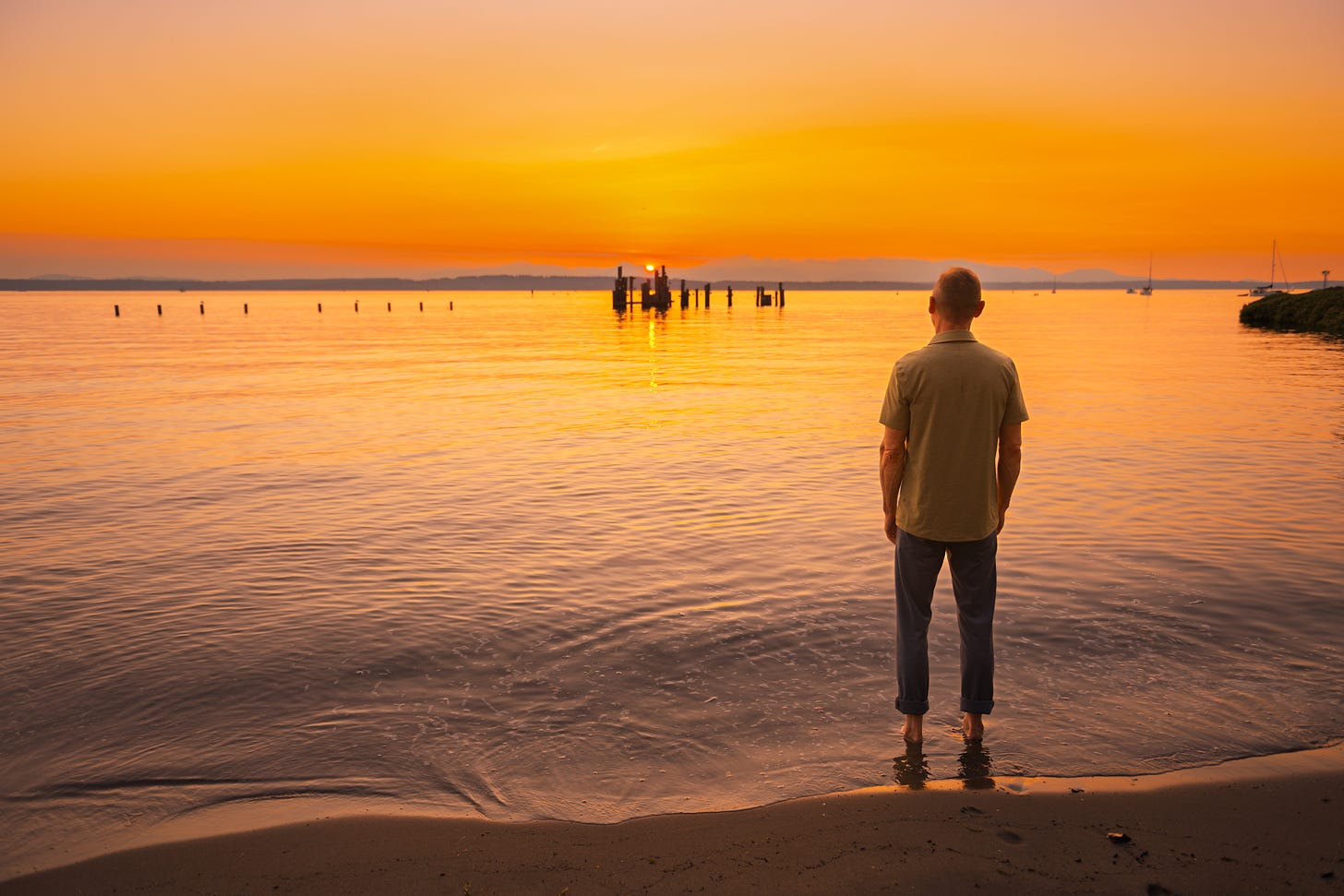 Sunset over Western Washington State. Mark looks at the orange, still sky and water.