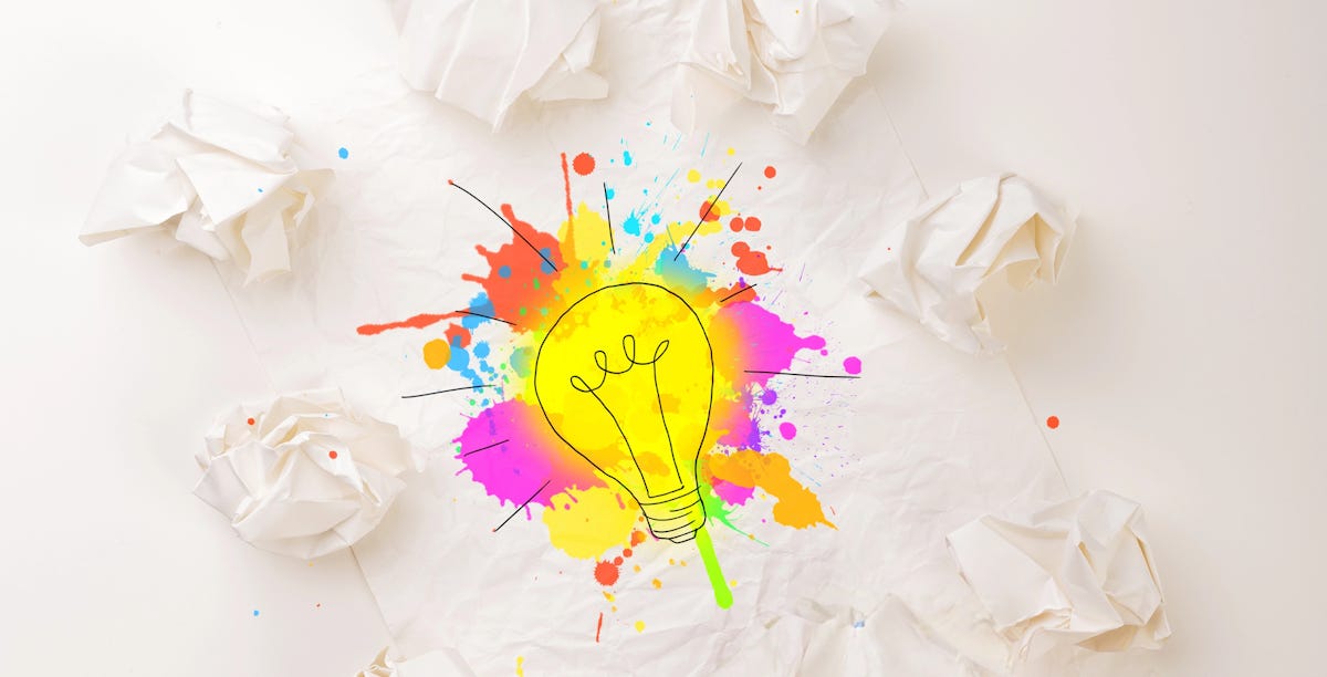 Multi-colored lightbulb drawing on and surrounded by crumpled paper