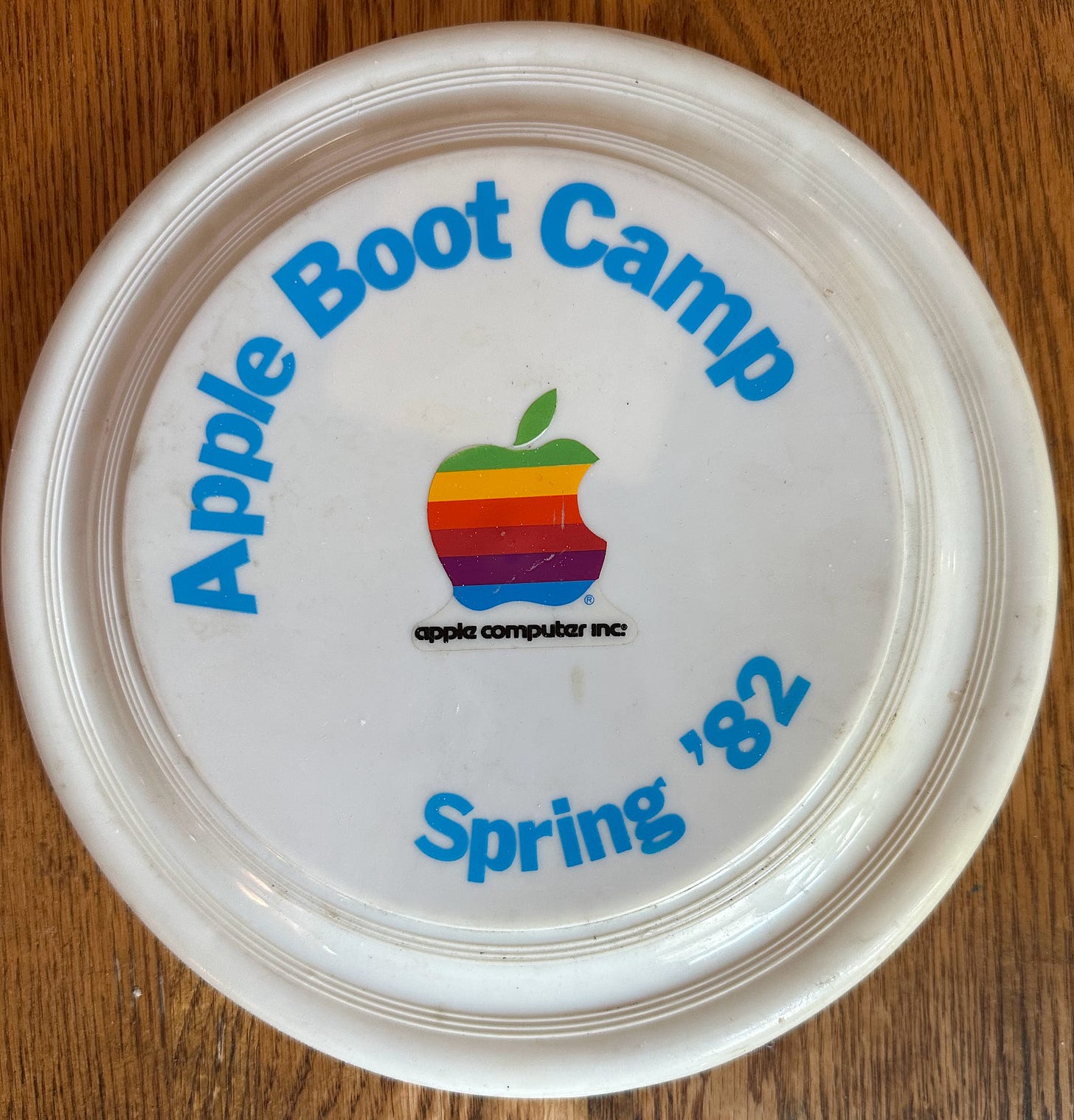 White frisbee labeled "Apple Boot Camp Spring '82" with six-color Apple logo sticker in the center.