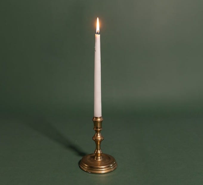 A single white candle sitting on top of a table