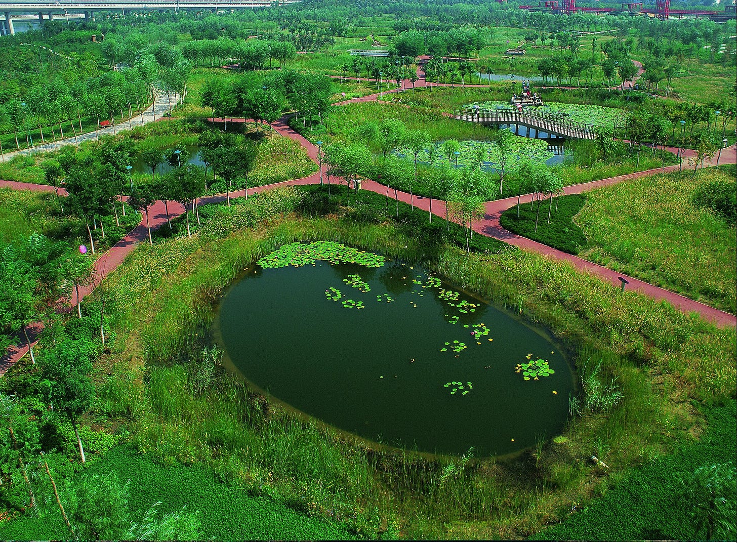 Aerial view of Qiaoyuan Park in Tianjin, China, showcasing various green infrastructure elements like bioswales, rain gardens, and permeable pavement. Aerial view of Qiaoyuan Park in Tianjin, China, showcasing various green infrastructure elements like bioswales, rain gardens, and permeable pavement.
