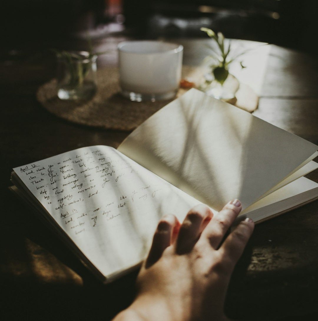 a person's hand holding an open book on a table