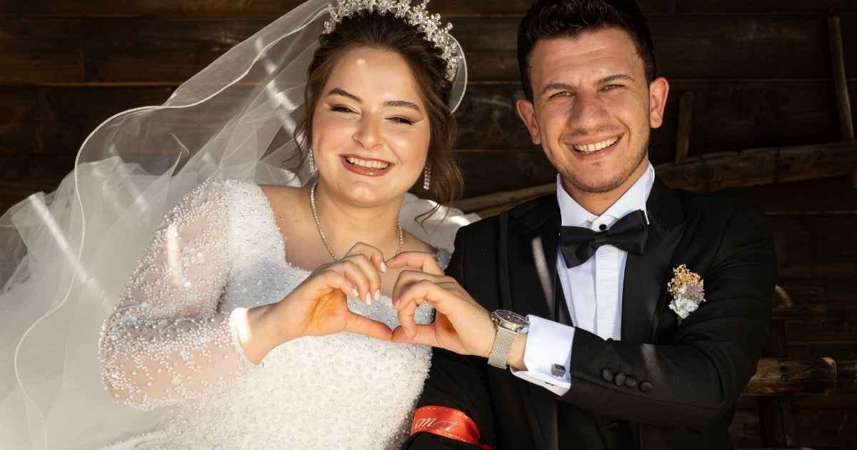 Smiling bride and groom creating heart shape with hands in an outdoor wedding setting Smiling bride and groom creating heart shape with hands in an outdoor wedding setting