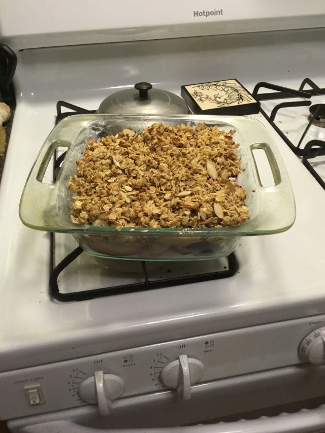 A breakfast crisp sitting on a cluttered and dirty stove A breakfast crisp sitting on a cluttered and dirty stove