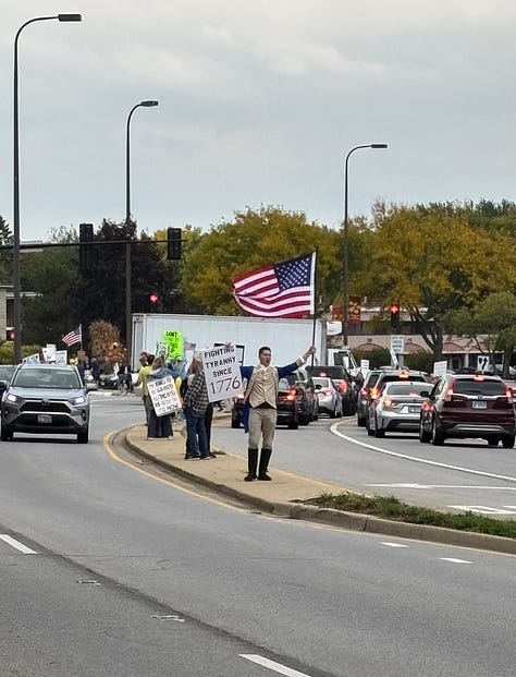 Various protesters and dogs with signs at a NO KINGS rally