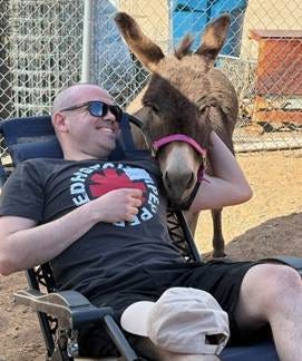 A person sitting in a chair with a donkey behind him

AI-generated content may be incorrect.