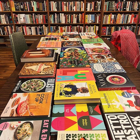 Table of colorful books, Sister Outside by Audre Lorde, Ymani and Ina smiling, Table with food, Ymani leaving a conference in an elevator, Cold brew coffee and plants.
