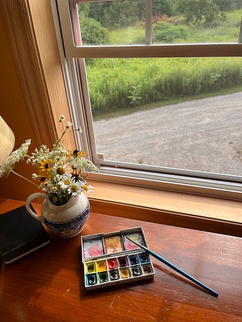 Six photos: one of a cockapoo walking through a field of wildflowers; some watercolour paints sitting by a window near a jug of flowers; a hummingbird moth visiting som bee balm; a rudimentary painting of a jar of jam and some blueberries; a person, barefoot, holding a mug of coffee, a dog leash around their neck; a book open in a lap, a dog sleeping on the couch beside them 