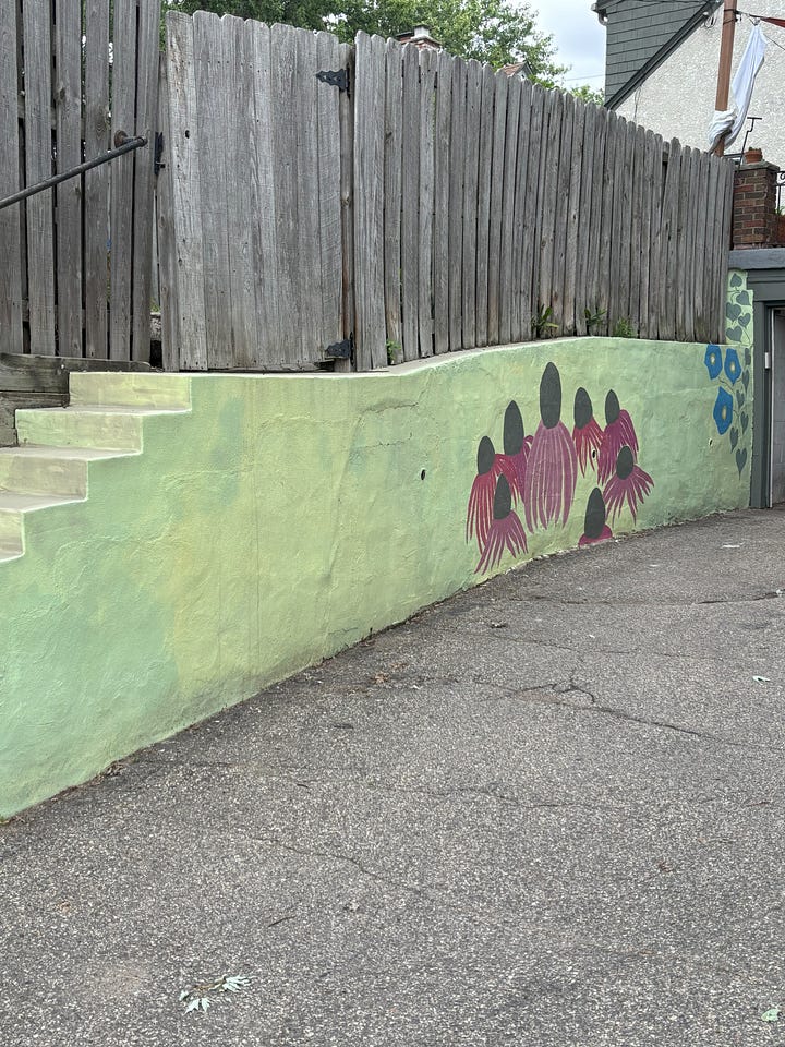 Four photographs of a mural in progress. Giant morning glory and echinacea blossoms on a light green background.