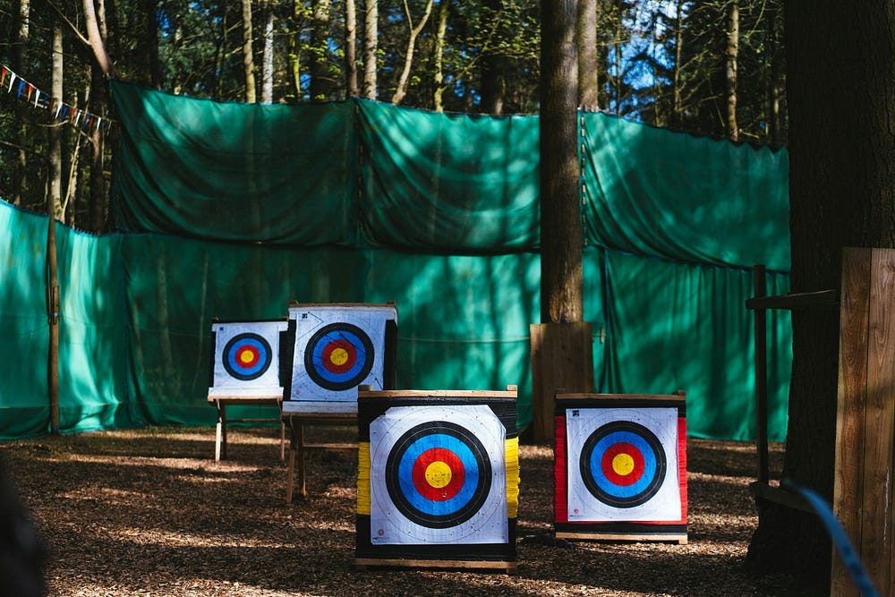 Four bullseye targets outdoors in a wooded area for archery