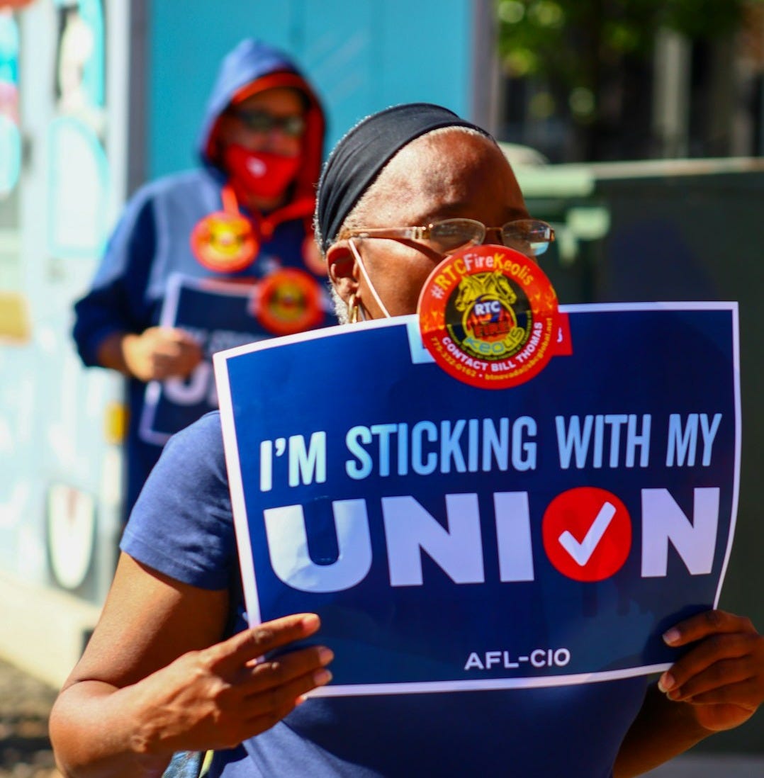 a woman holding a sign that says i'm sticking with my union