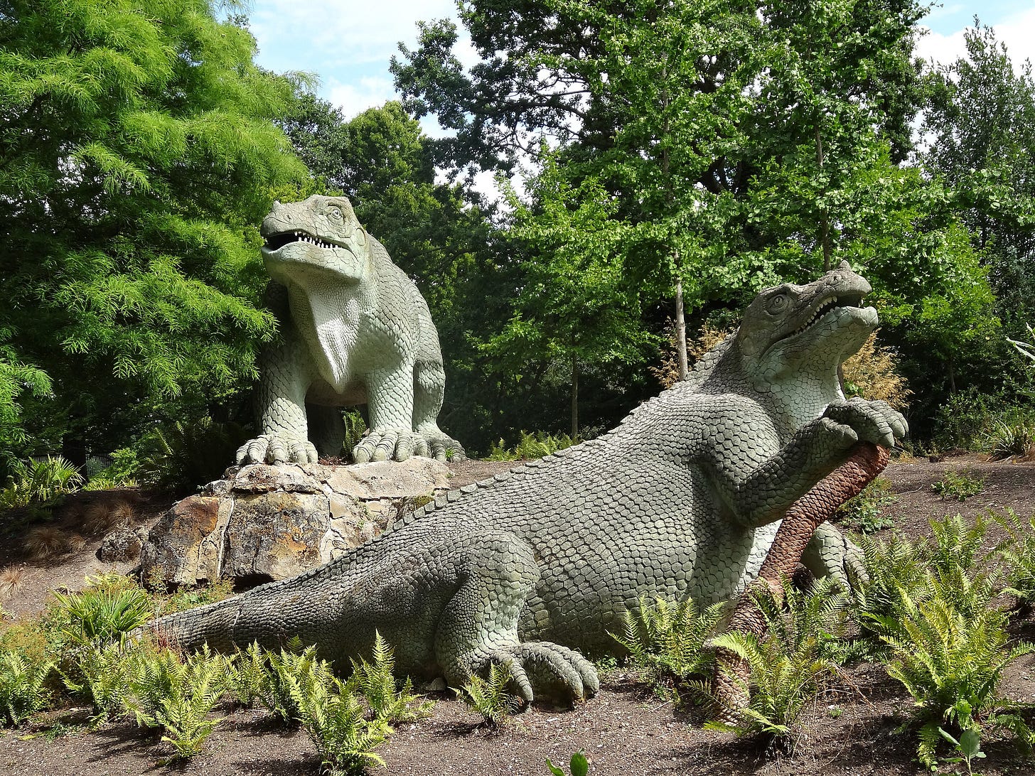 two concrete dinosaurs in woodland setting