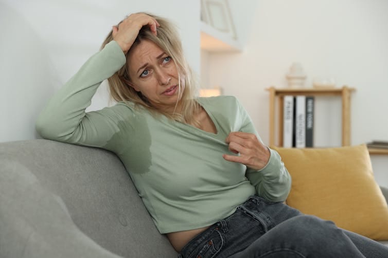 A woman sweats because of a hot flush. A woman sweats because of a hot flush.
